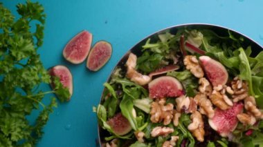 hands of male chef preparing healthy green salad with figs and walnuts in kitchen