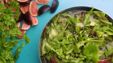 hands of male chef preparing healthy green salad with figs in kitchen, washing leafy greens