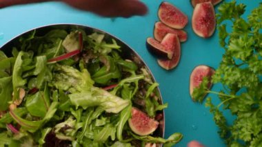 hands of male chef preparing healthy vegan green salad with figs and walnuts in kitchen