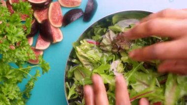 Video shows a person mixing a bowl of green salad with figs for a healthy meal. 8 seconds video 