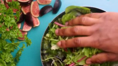 Video shows a person mixing a bowl of green salad with figs for a healthy meal. 8 seconds video 