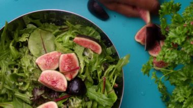 15 seconds video. Video shows a chef preparing a healthy green salad with sliced figs in a kitchen.