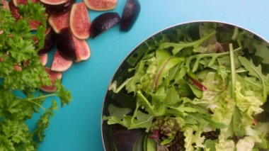hands of male chef preparing healthy green salad with figs in kitchen