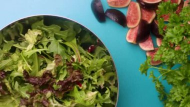 hands of male chef preparing healthy green salad with figs in kitchen