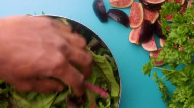 hands of male chef preparing healthy green salad with figs in kitchen