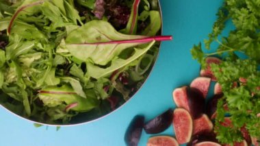 hands of male chef preparing healthy green salad with figs in kitchen