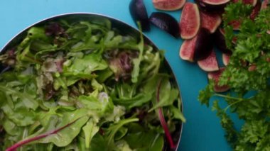hands of male chef preparing healthy green salad with figs in kitchen, washing leafy greens