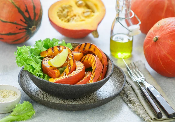 Delicious light salad of grilled pumpkin slices and lettuce with sesame seeds, lemon juice and olive oil. Healthy diet, vegetarian snack. Selective focus