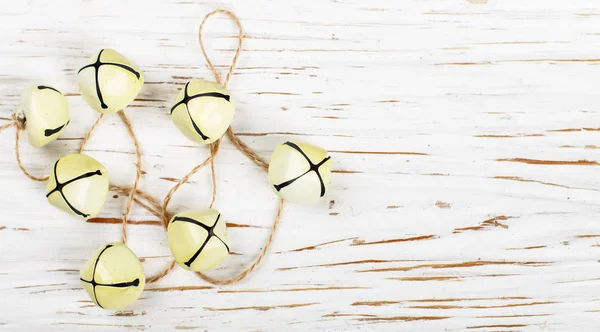 Christmas decoration-yellow jingle bells on the old white table. New year. The concept of the celebration.  Rustic style. Copy space and selective focus