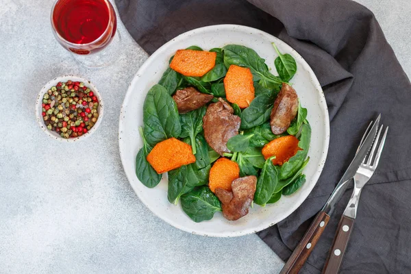 Warm spinach salad with chicken liver and baked pumpkin. Delicious dinner with red wine for gourmets. Selective focus, top view