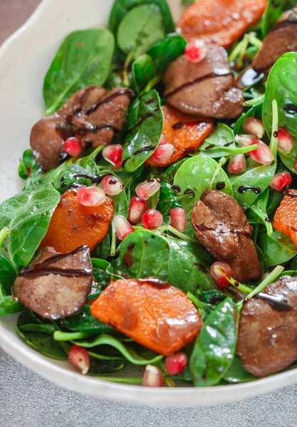 Warm spinach salad with chicken liver, baked pumpkin and pomegranate with spices and balsamic. Delicious dinner for gourmets. Selective focus