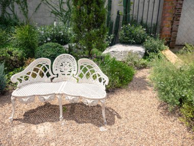 Yazın güzel, gölgeli bir bahçeye yerleştirilmiş beyaz metal şezlonglar boş..