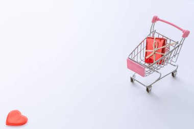 Kırmızı kalp, arka planda küçük alışveriş arabasında. Aşk ve alışveriş konsepti.