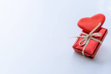 Hediye kutusu ve hafif arka planda pürüzsüz kumaştan yapılmış dekoratif kalp. Tatil tebriği kavramı