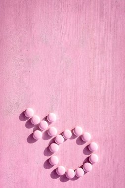 Pembe arka planda haplardan yapılmış bir kadının cinsiyet sembolü. Erkekler ve kadınlar arasındaki ilişkiler. Kadınlar için ilaç kavramı. Kadın sağlığı menopozu, adet öncesi sendromu veya östrojen.
