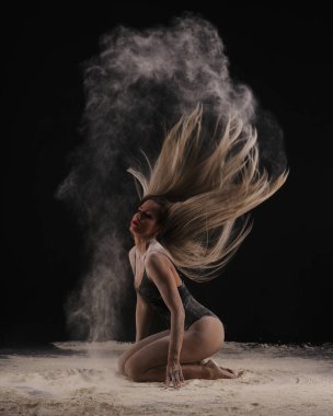 Güzel, seksi, zayıf, siyah vücutlu, uzun sarı saçlı, tozlu, unlu, siyah arkaplan tozlu bir dansçı..
