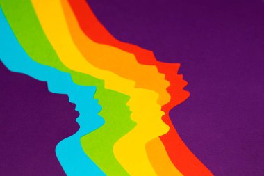 Cinsiyet ayrımı olmayan profiller gökkuşağı kağıdından kesilir ve mor kağıdın üzerinde çapraz olarak yatar. Mesajlaşmak için bir yer var. Özel tasarımın için kağıt resimleri..