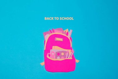 Okul aksesuarları olan el yapımı sırt çantası mavi arka planda pembe kağıttan kesilmiş. Kağıt sanatının fotoğrafı okul tasarımı için yapıldı..