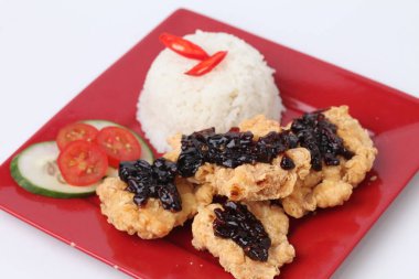 Kırmızı tabakta kızarmış tavuk ve pilav. Beyaz arka planda siyah baharatlı.