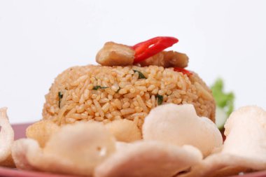 Endonezya yemeği: kızarmış pirinç (nasi goreng) beyaz arka planda kırmızı tabakta karides krakerleri servis edilir.