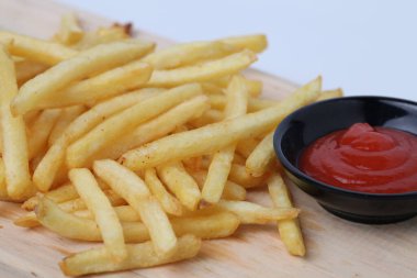 Lezzetli patates kızartması ya da kentang goreng kesim tahtasında, ahşap masa üzerinde, beyaz arka planda izole