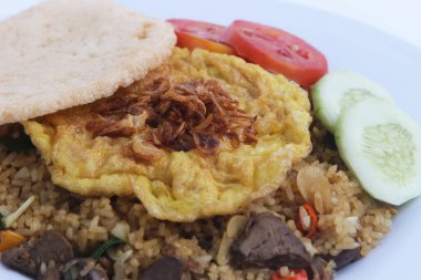 Nasi Goreng pilavı, Pete ve yumurta ile süslenmiş taze salatalık dilimleri ve bez üzerinde karides krakerleri. Asya yemekleri.