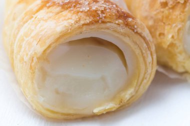 Beyaz kremalı puf böreği ya da beyaz arka planda vla susu. Aynanın arka planında beyaz kremayla dolu şişme boynuz, yakın plan..