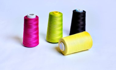 Beyaz üzerine izole edilmiş farklı renklerde dört dikiş ipliği rulosu