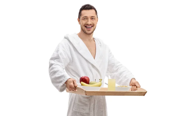 バスローブ姿で白い背景で隔離の朝食トレイを持って若い男 — ストック写真