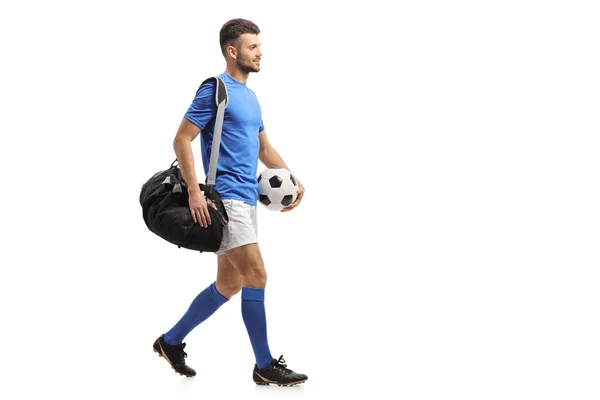 全长剖面拍摄的足球运动员与一个袋子和一个足球走在白色背景隔离 — 图库照片