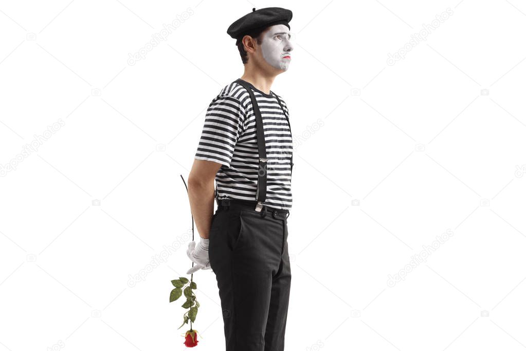 Sad mime holding a rose behind his back isolated on white background