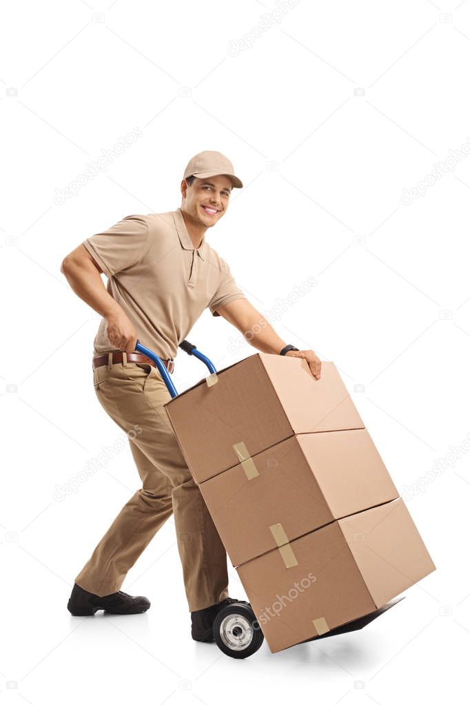 Delivery man with a hand truck loaded with boxes looking at the camera and smiling isolated on white background