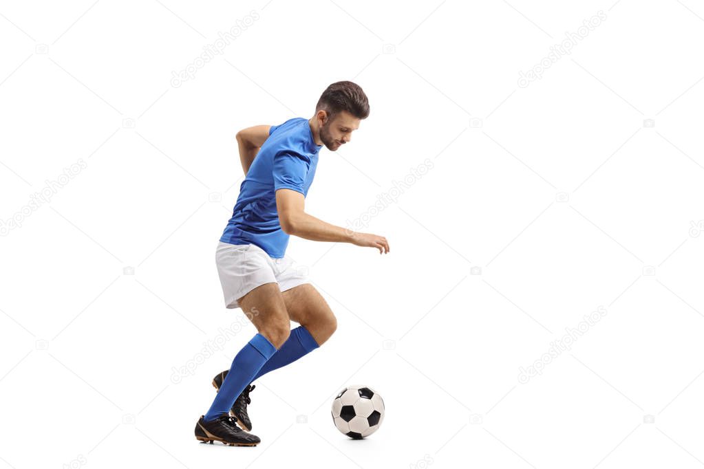 Full length profile shot of a soccer player dribbling isolated on white background