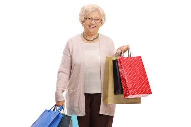 Yaşlı kadın ile alışveriş torbaları beyaz arka plan üzerinde kameraya bakarak ve gülümseyen izole