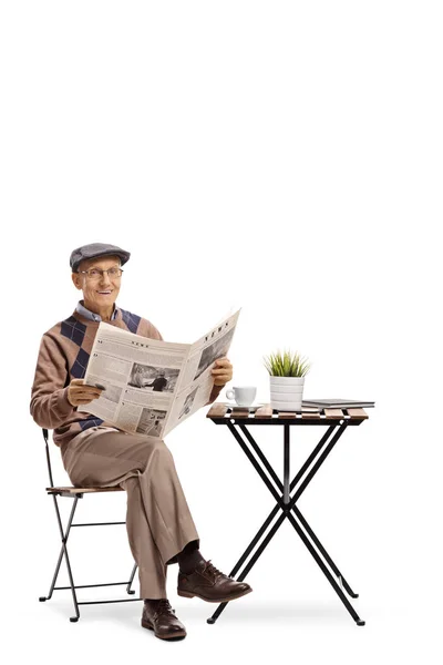コーヒー テーブルに座っていると 白い背景で隔離のカメラ目線の新聞と老人 — ストック写真