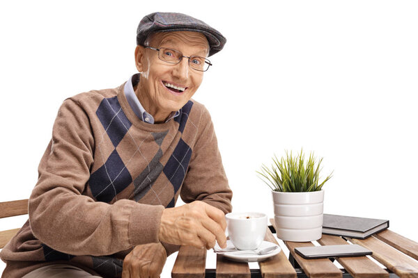 Elderly man sitting at a coffee table and smiling isolated on white background