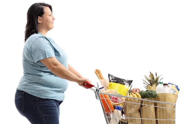 買い物カゴを持つ若い女性が白い背景で隔離の食料品でいっぱい — ストック写真