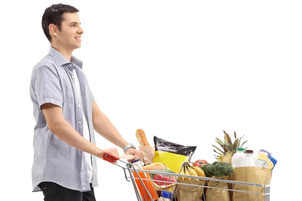 買い物カゴを持った若い男が白い背景で隔離の食料品でいっぱい — ストック写真