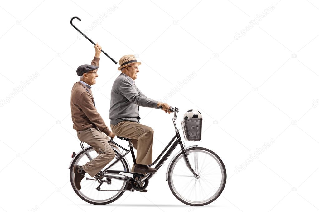 Joyful seniors with a cane and a football riding a bicycle together isolated on white background