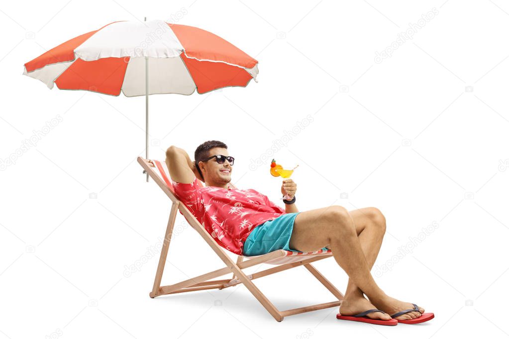 Tourist with a cocktail sitting in a deck chair with an umbrella isolated on white background