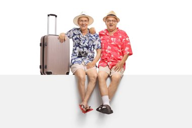 Bir panel üzerinde oturan ve beyaz arka plan üzerinde izole kamera bakarak yaşlı turistler