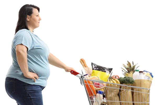 買い物カゴを持つ若い女性が白い背景で隔離の食料品でいっぱい — ストック写真