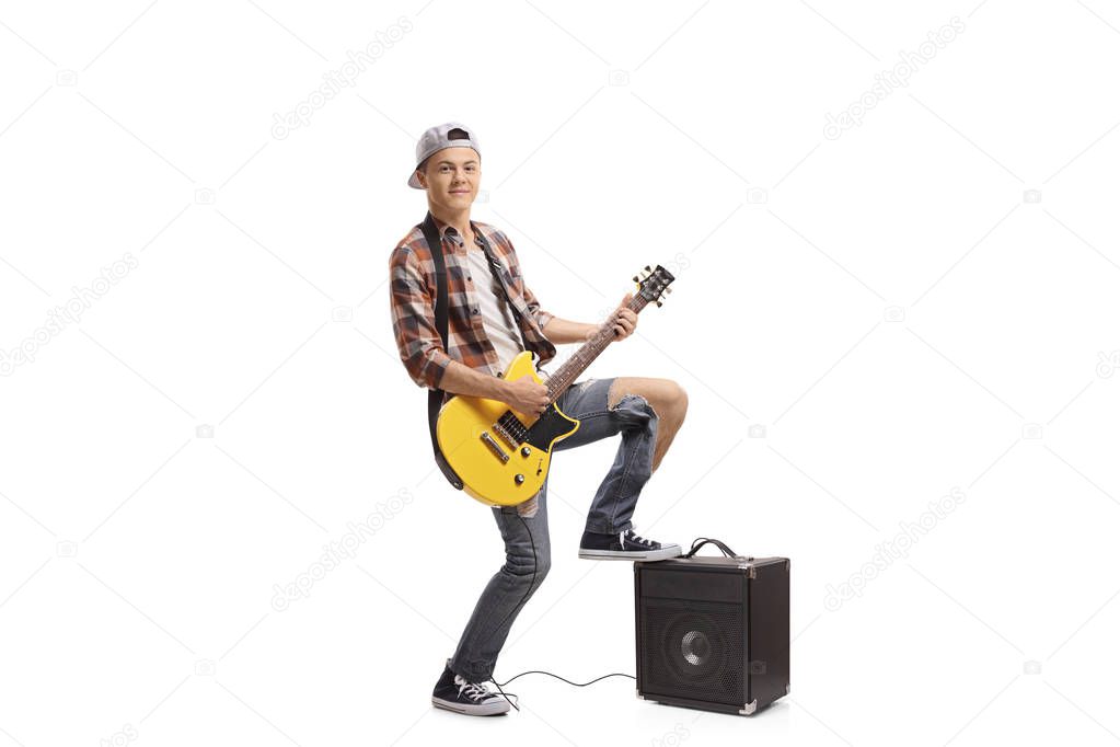 Full length portrait of a teenager playing an electric guitar isolated on white background