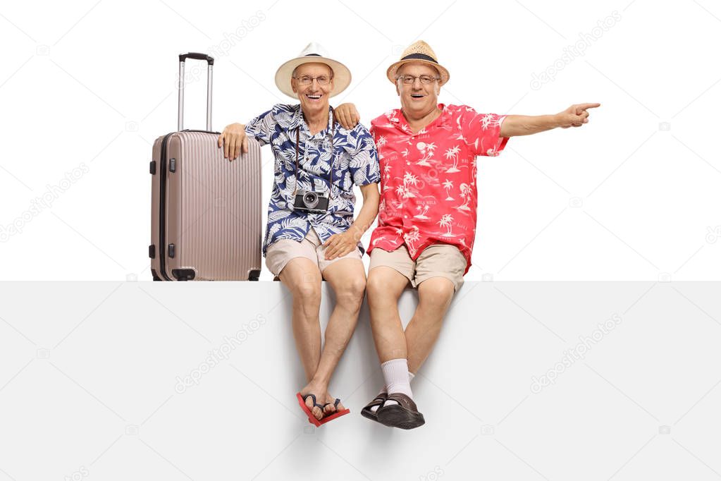 Two elderly tourists sitting on a panel with one of them pointing isolated on white background
