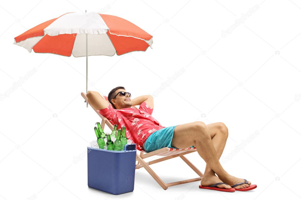 Tourist lying in a deck chair with an umbrella next to a cooling box filled with bottles of beer isolated on white background