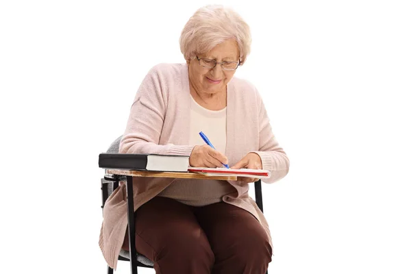 Ηλικιωμένη Γυναίκα Κάθεται Μια Καρέκλα Σχολείου Και Λήψη Σημειώσεων Που — Φωτογραφία Αρχείου