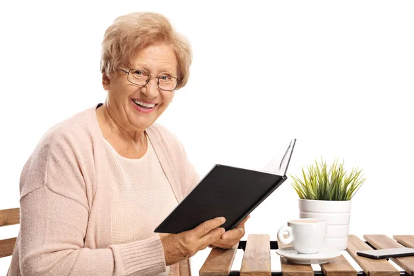 Äldre Kvinna Med Bok Sitter Ett Soffbord Och Tittar Mot — Stockfoto