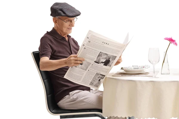 白い背景に分離された新聞を読むレストランのテーブルに着席しているシニア — ストック写真