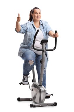 Başparmak yukarıya üstünde izole beyaz arka plan ile sabit bir bisiklet üzerinde egzersiz bir kilolu kadın portresi tam uzunlukta