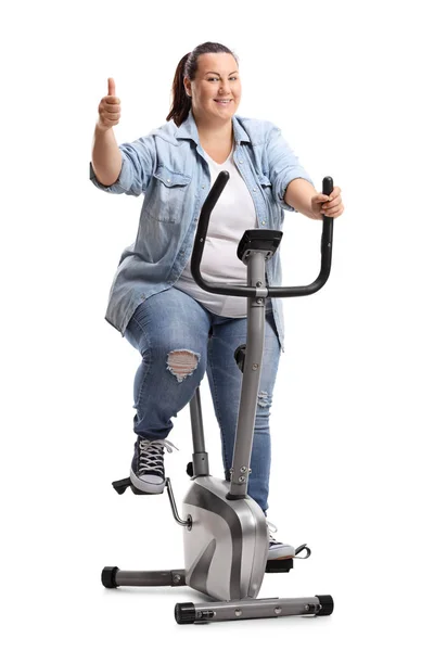 一个超重妇女在固定的自行车上锻炼的全长肖像 拇指在白色背景上被隔离 — 图库照片